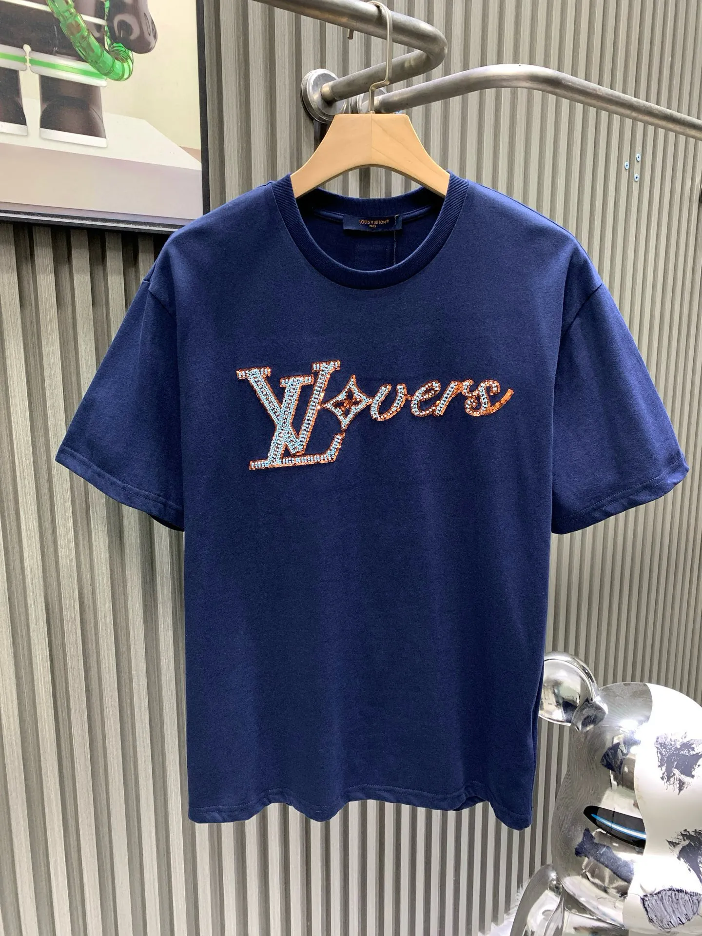 🅿️240 🀄️ Louis Vuitton 1V 2025 new hand-beaded embroidered short-sleeved T-shirt 40S pure cotton plain 100% cotton fabric 280g This T-shirt is made of soft cotton and uses beaded embroidery to express the 1V Lovers logo. It can inject an elegant atmosphere into daily looks. The fabric has good breathability and sweat permeability and can absorb sweat and micro-perspiration from human skin. It is more comfortable to wear in summer without sticking to the human body, and truly achieves breathable and sweat-absorbing effects. Sequin embroidery is also called bead embroidery or sequin embroidery. It is a type of embroidery machine. Materials with a hard texture, flat surface and high smoothness are selected to place the sequins on the fabric in the specified direction. At the same time, the embroidery needle pierces the fabric at the center of the sequins to fix the position of the sequins. The beaded part has a protruding three-dimensional surface, forming a full, embossed and undulating effect. The three-dimensional texture beads that add patterns are dyed with the original color to create a gradient beading effect. The color effect is saturated and bright, covering the entire surface and achieving the original effect. The number of particles is clear, and the overall three-dimensional effect is outstanding.